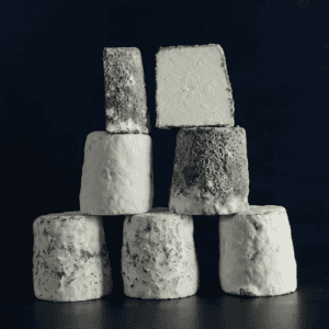 Assorted artisanal cheeses stacked artistically on dark background
