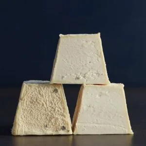 Stacked blue cheese wedges on dark background