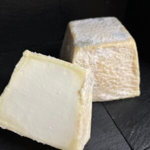 Soft white cheese with rind on black background.