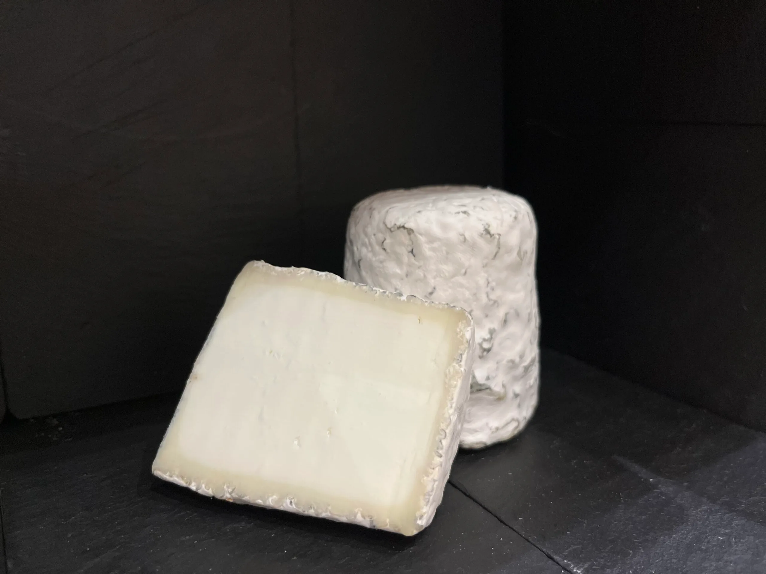 Brie and blue cheese on a black background