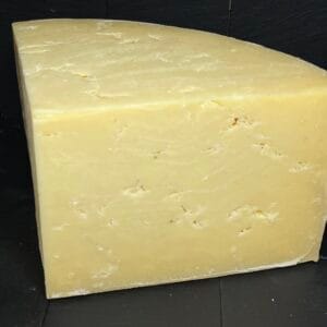 Large wedge of aged yellow cheese on dark backdrop
