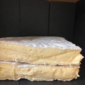 Stacked slices of creamy soft cheese on black background