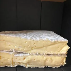 Stacked slices of creamy soft cheese on black background
