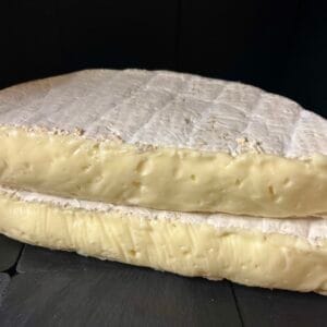 Close-up of creamy brie cheese wedge on black background
