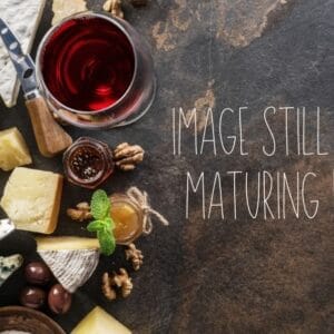 Assorted cheeses, wine, and nuts on dark stone surface