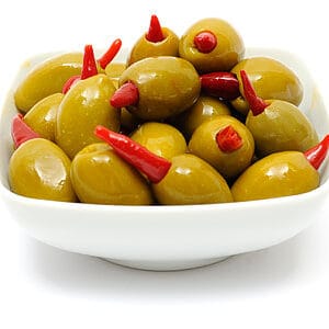 Green olives stuffed with red peppers in white bowl