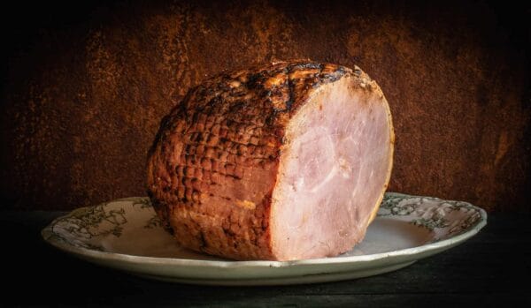 Grilled ham on decorative plate against dark background