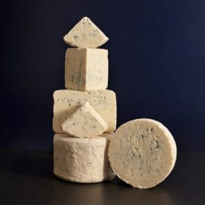 Stacked various blue cheeses on dark background