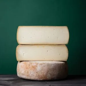 Stacked artisan cheese wheels against green background