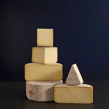 Stack of assorted cheeses on dark background