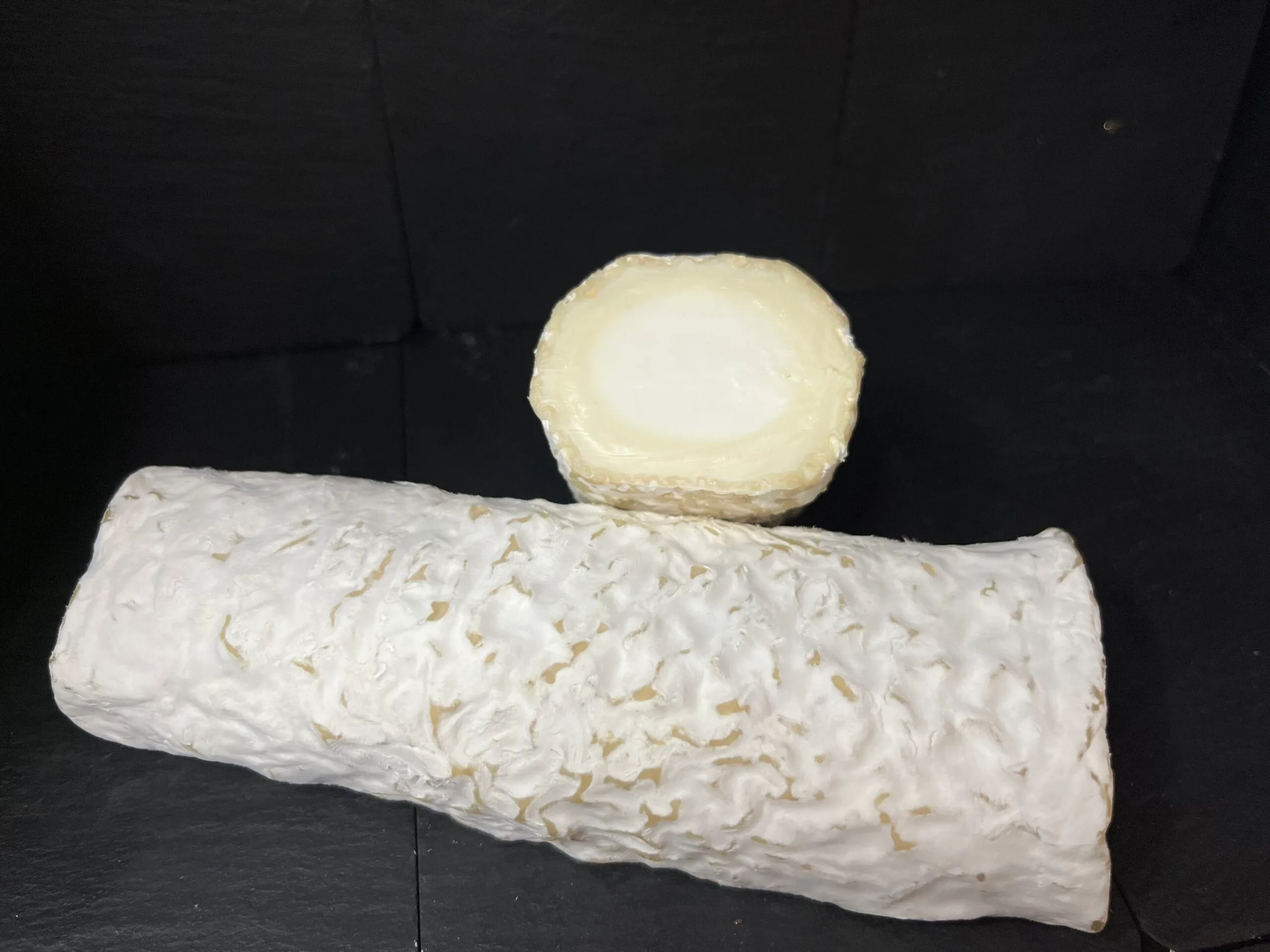 Artisanal goat cheese varieties on dark background