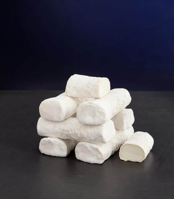 Stack of soft white goat cheese logs on table