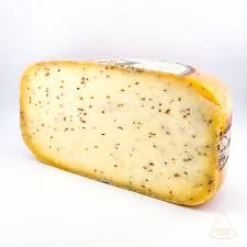 Herb-infused cheese wedge on white background