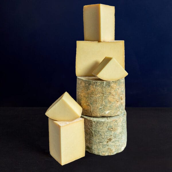 Stacked assorted hard cheeses on dark background