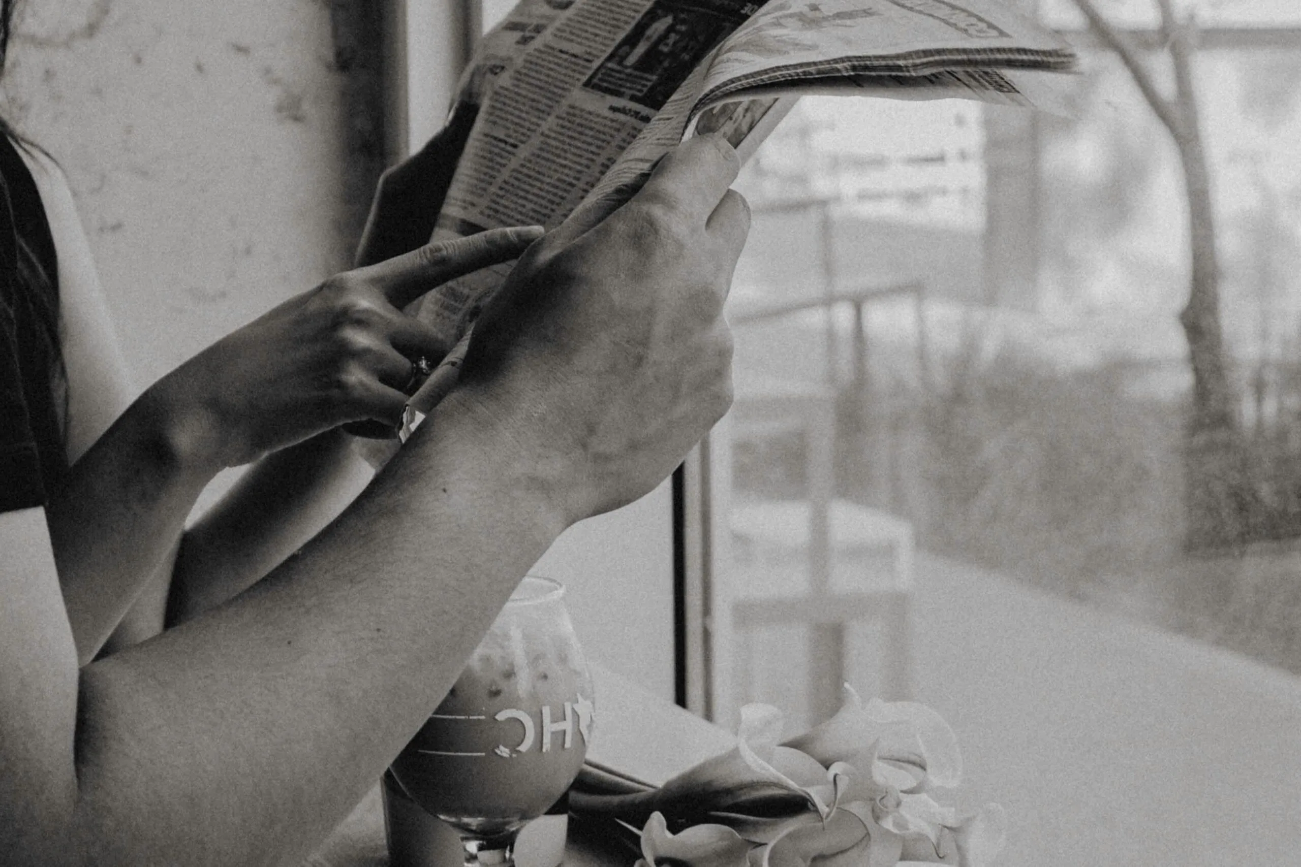 Couple reading newspaper by window with drink