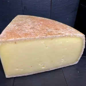Wedge of artisan cheese on black background