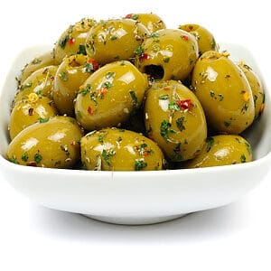 Seasoned green olives in white bowl isolated on white