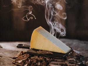 Smoked cheese wedge on rustic wooden surface