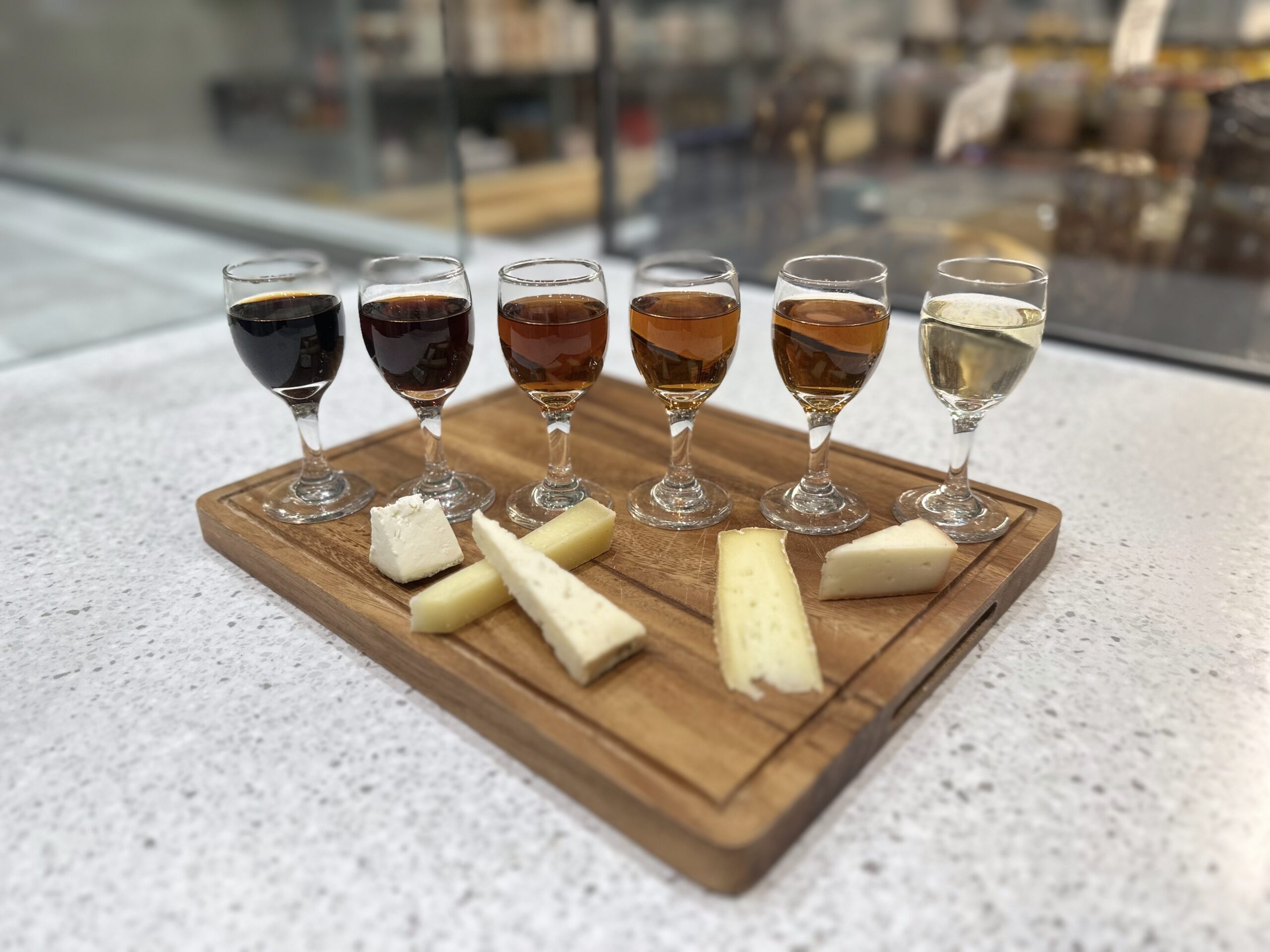 Assorted wines and cheeses on wooden board