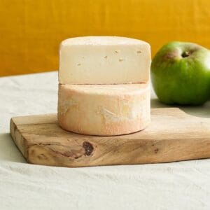 Aged cheese on wooden board with green apple