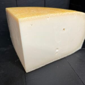 Wedge of hard cheese on dark wooden background