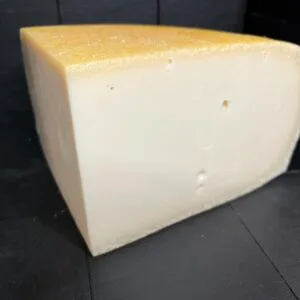 Wedge of hard cheese on dark wooden background
