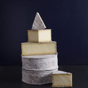 Stacked artisan cheese tower against dark background