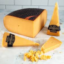 Aged cheddar cheese on white marble surface