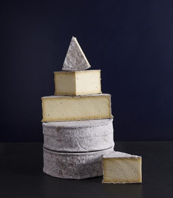 Stacked artisan cheese tower against dark background