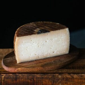 Aged cheese on wooden board against dark background