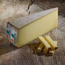 Comté cheese wedge and slices on wooden surface