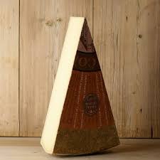 Wedge of aged cheese with rind on wooden background