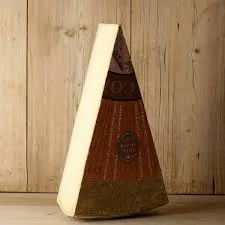 Wedge of aged cheese with rind on wooden background