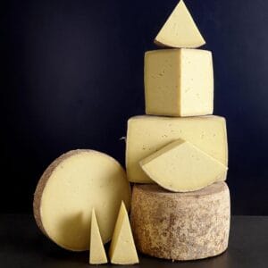 Stacked assorted artisan cheeses on dark background