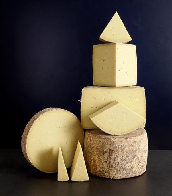 Stacked assorted artisan cheeses on dark background