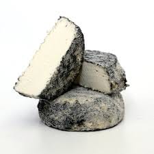 Sliced ash-coated artisan cheese on white background