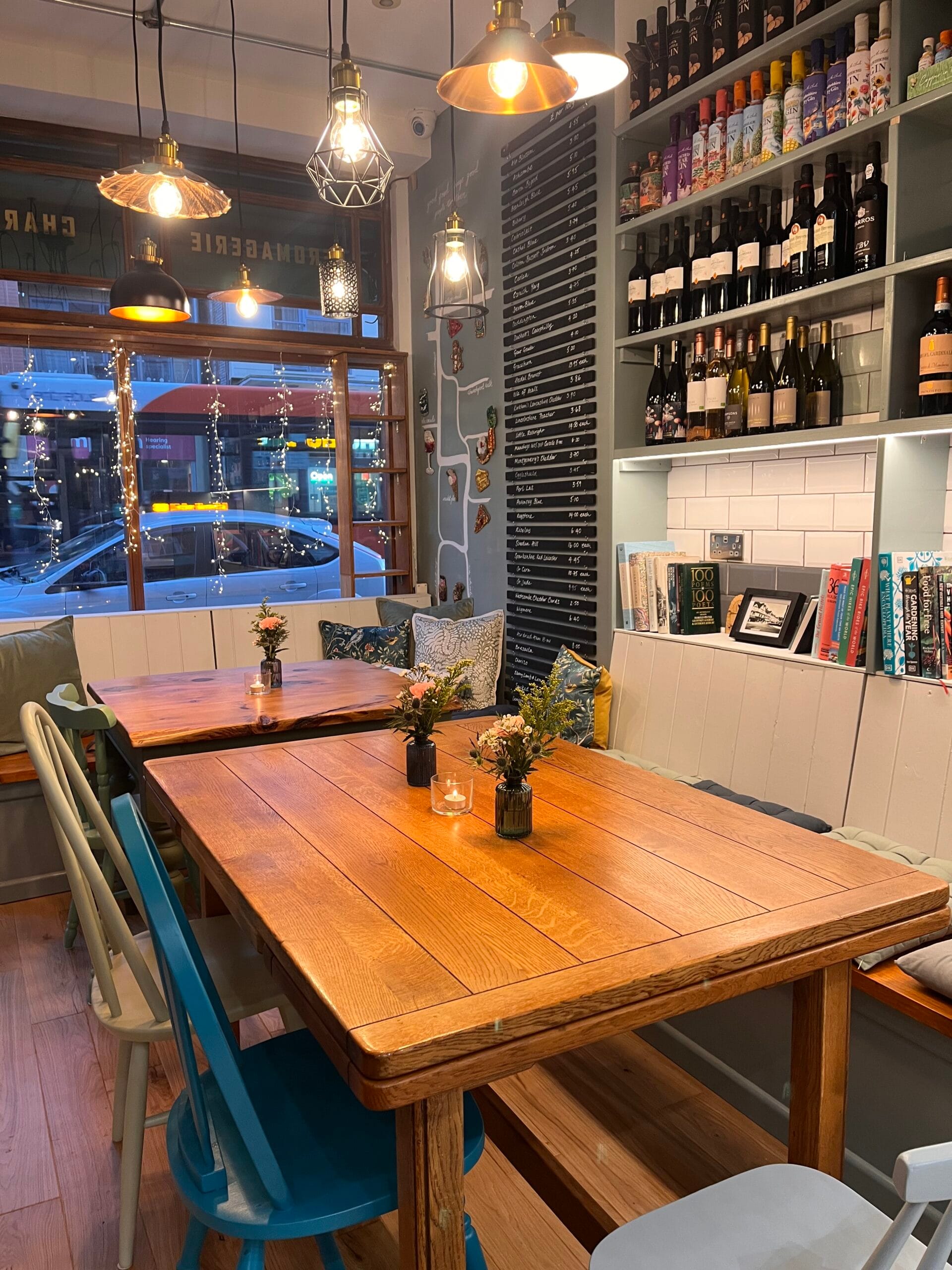 Cosy café tables beneath pendant lights and wine shelves