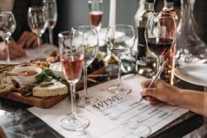 Guest marking wine tasting notes beside glasses and cheese