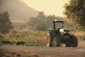 Green tractor on a rural road at sunset