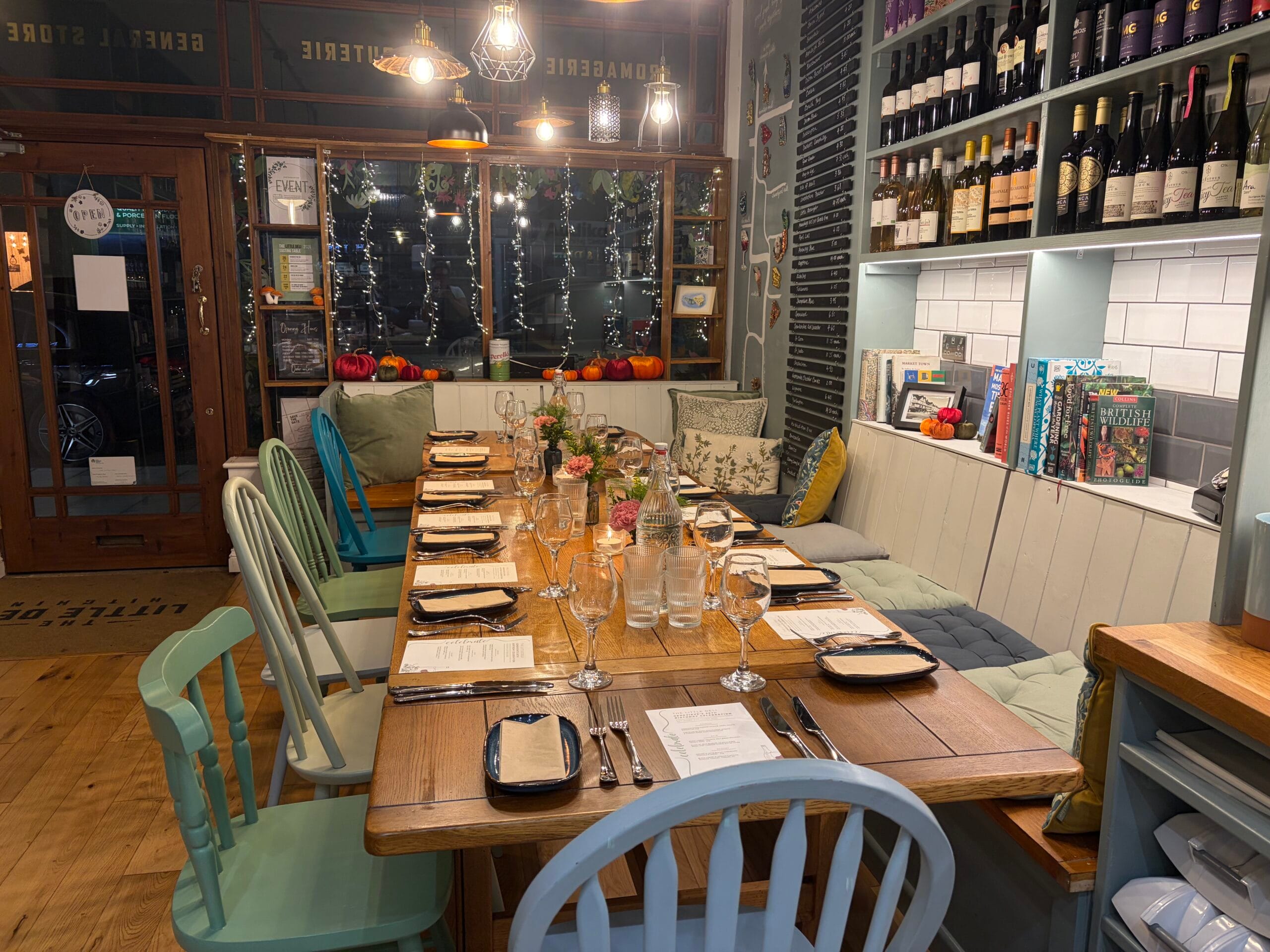 Wine bottles displayed above cosy restaurant tables and chairs